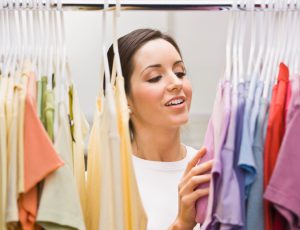 An attractive young female looking through a clothing closet. She is smiling. Horizontally framed photo.